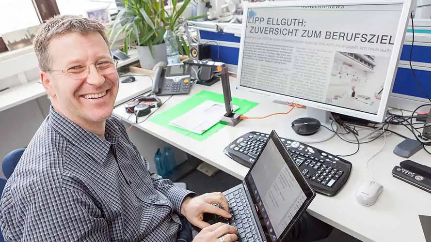 A SuperNova for Business user smiling at his desk while working
